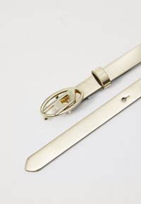 Ceinture en métal doré avec une boucle rectangulaire. La sangle est lisse, plate et présente une pointe, complétant le design brillant de la boucle.