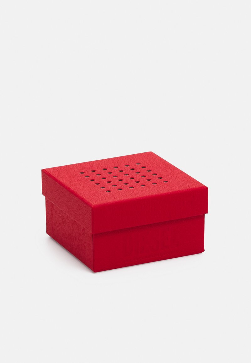 Scatola regalo quadrata rossa con texture, dotata di un coperchio perforato e logo in rilievo; superficie liscia con un design compatto.