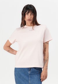 Lys rosa bomull t-skjorte med rund hals og korte ermer, med en liten, subtil Calvin Klein-logo på brystet. Glatt tekstur.