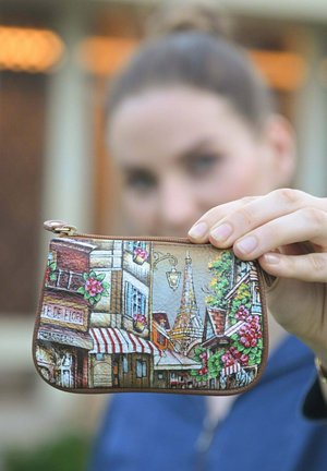 Colorful leather coin purse featuring Parisian street scenes, detailed with buildings, flowers, and the Eiffel Tower, accented with a gold zipper.