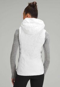 Gilet bianco isolato con cappuccio, caratterizzato da una superficie liscia e un design aderente sul retro. Maniche lunghe grigie visibili sotto.