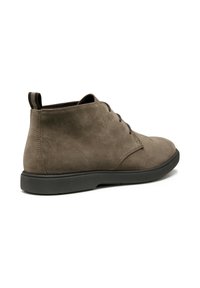 Botines de ante gris con punta redonda, suela de goma negra de perfil bajo y una asa en la parte posterior para facilitar su uso. Diseño minimalista.