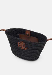 Svart vävd korg med en brun läderdetalj som har en logotyp, rund form och öppen toppdesign. Texturerad yta med kontrasterande material.