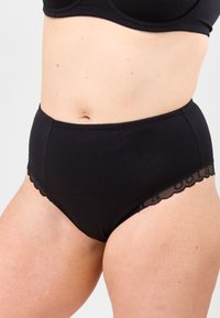 Svart höga trosor i mjukt tyg, med en vågig spetskant längs midjan för extra detalj.