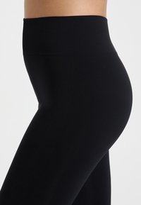 Leggings negras de cintura alta fabricadas con una tela elástica. Textura suave con un ajuste ceñido, diseñadas para contornear el cuerpo.