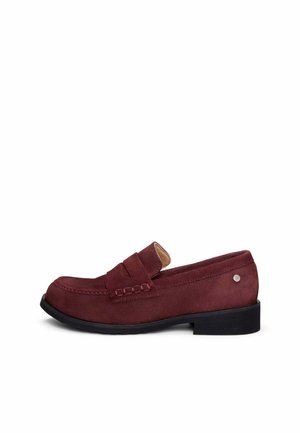Mocasín de ante burdeos para hombre con tira de moneda, puntera redonda, tacón bajo negro y pequeño emblema metálico en el lateral.