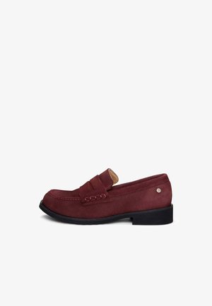Mocasín de ante burdeos para hombre con tira de moneda, puntera redonda, tacón bajo negro y pequeño emblema metálico en el lateral.