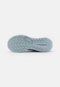 Semelle de chaussure de sport bleu clair avec un motif de rainure texturé, incluant des formes géométriques et un petit logo en relief au centre.