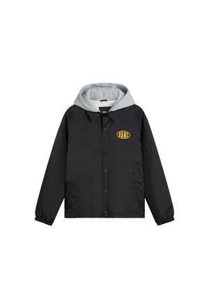 Giacca nera con cappuccio grigio, dotata di chiusura frontale a pressione e tasche laterali. Logo giallo "VANS" nella parte superiore sinistra del petto.