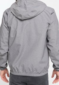 Harmaa hupullinen takki, jossa on joustavat kalvosimet ja vyötärönauha. Takki on valmistettu sileästä, kevyestä kankaasta, ja siinä on yksinkertainen, koristelemattoman tyylikäs muotoilu.