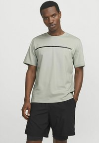 Lysegrå t-shirt med en sort horisontal accentlinje, parret med sorte shorts. T-shirten har en rund hals og korte ærmer, glat tekstur.