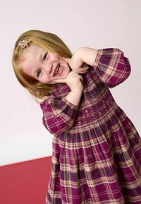 Rochie cu carouri mov, cu mâneci lungi, bust prins și accente de fir aurie. Țesătură ușoară cu fustă evazată. Accesoriu de agrafă pentru păr.