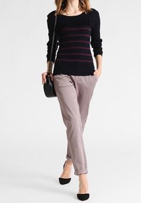 Navy sweater with vertical burgundy stripes and a ruffled neckline, paired with light gray tapered trousers and black pointed-toe heels.