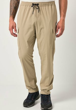 Pantaloni cargo leggeri beige con vita elastica e cordino, dotati di tasche laterali e polsini affusolati, abbinati a scarpe nere.