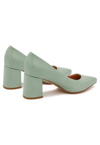 Scarpe con tacco verde in pelle liscia, con punta affusolata e tacco a blocco. Il tacco è di un colore tan a contrasto per un tocco di dettaglio in più.