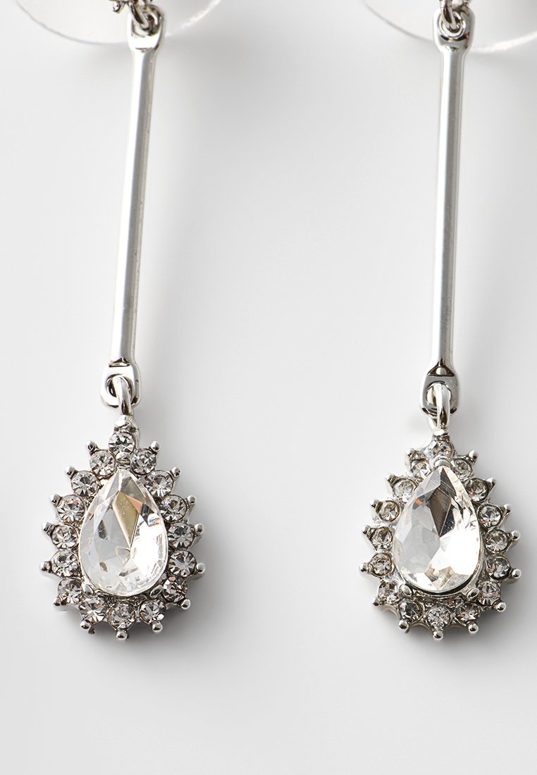 Orecchini a goccia in tono argento caratterizzati da cristalli trasparenti a forma di pera circondati da cristalli trasparenti più piccoli, con un design elegante e allungato.