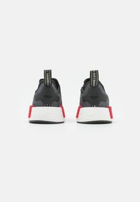 Black athletic shoes with a textured upper, red heel accents, and white boost sole. Features a logo on the heel and pull tab.