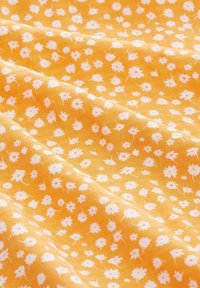 Żółta tkanina z rozsianym wzorem małych białych kwiatków, o gładkiej teksturze i miękkim układzie, odpowiednia do różnych projektów krawieckich.