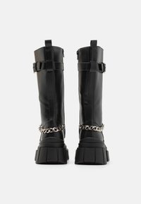 Μαύρες δερμάτινες μπότες μέχρι το γόνατο με χοντρή σόλα, φερμουάρ και ρυθμιζόμενες λουρίδες με λεπτομέρεια αλυσίδας στον αστράγαλο.
