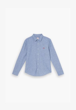 Ljusblå skjorta med knappar fram, lång ärm, krage och en liten röd logotyp på bröstet. Tyget har en mjuk, texturerad yta.