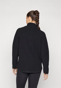 Black fleece pullover with a high collar, textured surface, and long sleeves. Features a rounded hem and relaxed fit.