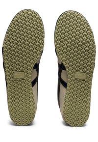 Black and beige slide sandals with textured rubber soles featuring triangular patterns and branding on the footbed.