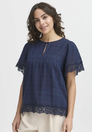 Blusa blu navy con tessuto testurizzato, caratterizzata da maniche corte e un delicato bordo in pizzo sull'orlo, valorizzata da un piccolo scollo a chiave frontale.