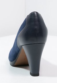Námořnický modrý vysoký podpatek s texturovaným semišem na vrchu a hladkým koženým podpatkem, s tapered tvarem a pevným gumovým podešví.