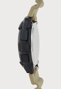 Montre numérique avec un bracelet en caoutchouc noir et beige, un cadran rectangulaire, des boutons texturés sur le côté et un dos métallique argenté.