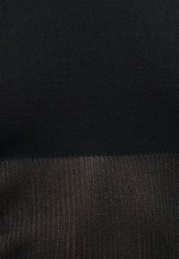 Κοντινό πλάνο μαύρου υφάσματος με λεία υφή στο πάνω μέρος και ριγέ, ελαφρώς αντανακλαστική πλεκτή υφή στο κάτω μέρος.