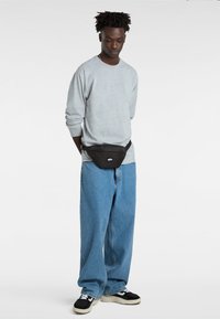 Szary sweatshirt, czarna nerka, niebieskie szerokie dżinsy, czarno-białe sneakersy. Prosty design, swobodny wygląd, luźny krój, minimalne detale.