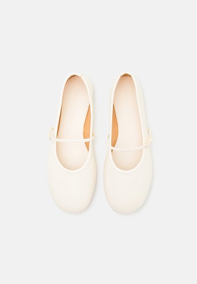 White leather ballet flats with a rounded toe, thin ankle strap, and soft interior. Smooth surface with minimal stitching details.