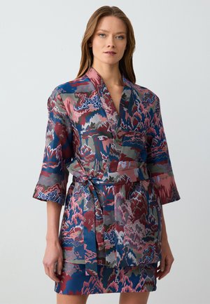 Accappatoio con pattern che presenta colori rosso, blu e grigio. Realizzato in un materiale lucido, con cintura e maniche a 3/4. Contiene motivi astratti di montagne.