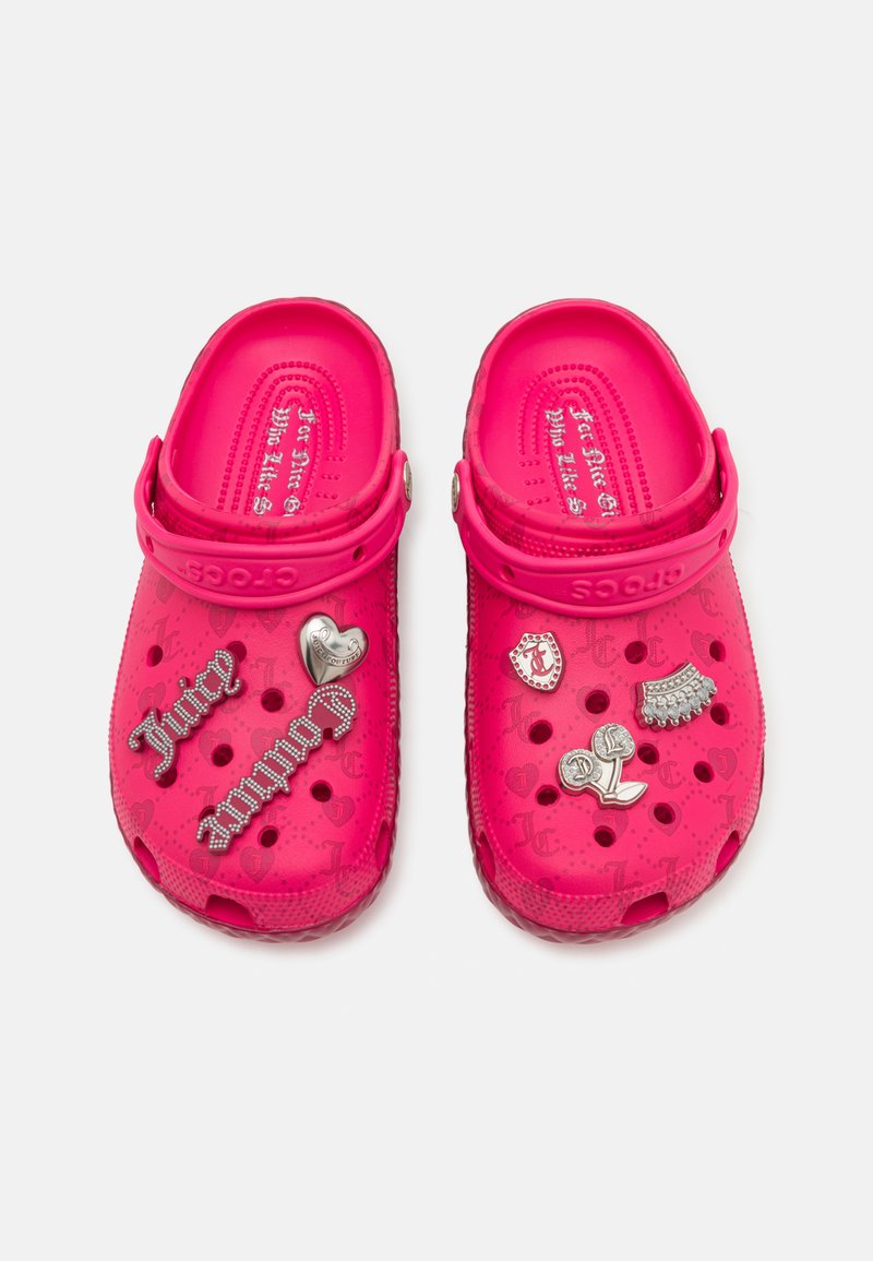 Zuecos de color rosa brillante, fabricados en material ligero con charms decorativos, perforaciones para ventilación y un diseño clásico de zueco.