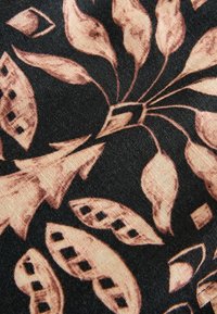 Tissu noir avec des motifs floraux et feuillages abstraits marron, comprenant des découpes en forme de losange sur certaines feuilles.
