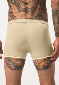 Beige bavlněné boxerky s jemnou texturou, s nenápadním pasem s embosovaným nápisem "JP1880" a kontrastním lemem na nohavicích.