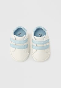 Λευκά αθλητικά παπούτσια με ανοιχτό μπλε λεπτομέρειες, με λουριά βέλκρο. Κατασκευασμένα από λείο υλικό με στρογγυλεμένη μύτη και επενδυμένο εσωτερικό. Μέγεθος 17.