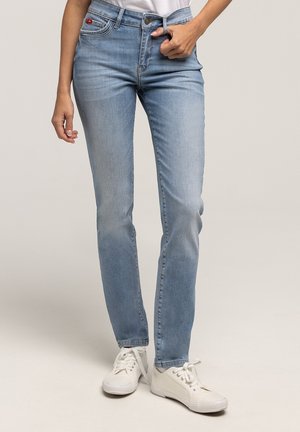 Jasnoniebieskie dżinsy o dopasowanym kroju, z pięcioma kieszeniami, pojedynczym zapięciem na guzik oraz kontrastowymi przeszyciami. W połączeniu z białymi trampkami.