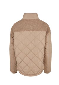 Beige gesteppte Jacke mit einer strukturierten, braunen Fleece-Oberseite auf dem Rücken, Stehkragen und elastischen Bündchen, die ein mattes Finish und ein gemütliches Design betont.