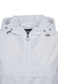 Giacca bianca a vento con cappuccio, dotata di zip metà, hardware metallici, cordini e una tasca frontale. Tessuto liscio e leggero.