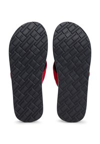 Sandales en tissu rouge avec une semelle en caoutchouc noir texturé présentant un motif en croisillons, conçues pour le confort et l'adhérence.