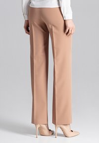 Beige op maat gemaakte broeken met een rechte pijp. Gemaakt van soepele stof, met een verborgen tailleband en minimale stikdetails.