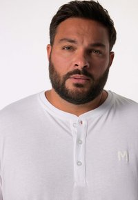 Weißes Kurzarm-Henley-Shirt mit Knopfleiste und kleinem Logo. Weiche Textur, runder Halsausschnitt und Standardpassform.