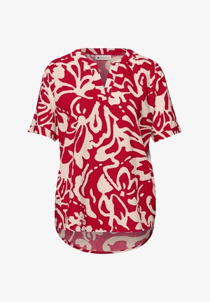 Červená a bílá halenka s abstraktním vzorem, krátkými rukávy, výstřihem do V a volným střihem, přední lem je mírně kratší než zadní.