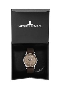Zegarek z srebrną kopertą, teksturowanym brązowym cyferblatem, wyświetlaczem daty, brązowym skórzanym paskiem oraz opakowaniem z logo Jacques Lemans.