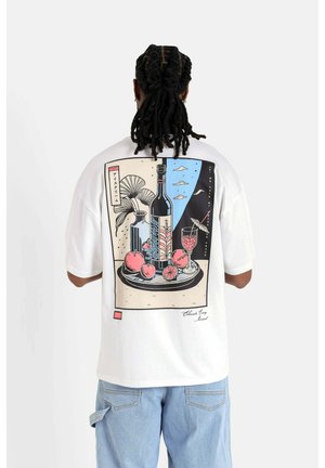 Hvid kortærmet t-shirt med en farverig illustration af en vinflaske og frugt på en tallerken, med abstrakte elementer og tekst.
