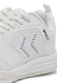 Scarpe da ginnastica bianche con una superficie in mesh testurizzata, design a zigzag blu navy sul lato e una suola di gomma con un battistrada a motivo.