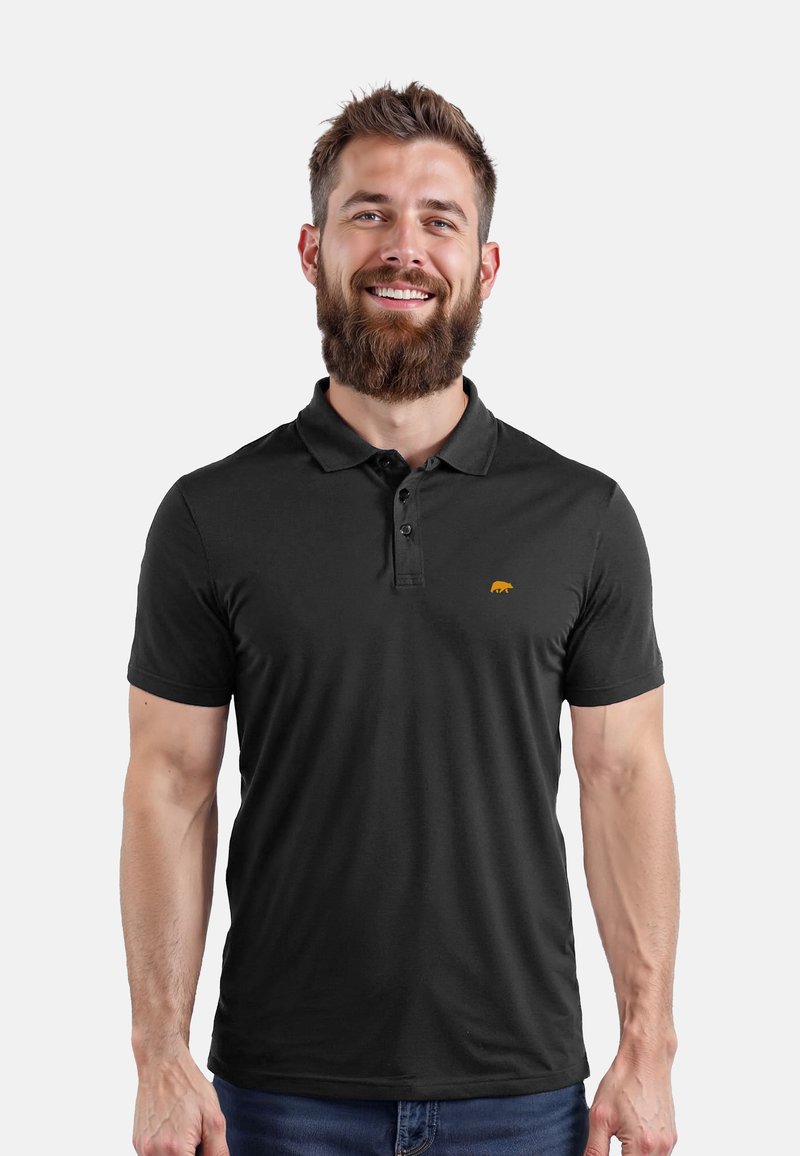 Polo nero realizzato in un tessuto liscio e traspirante. Presenta una pattina con tre bottoni e un piccolo logo di un orsetto arancione sul lato sinistro del petto.
