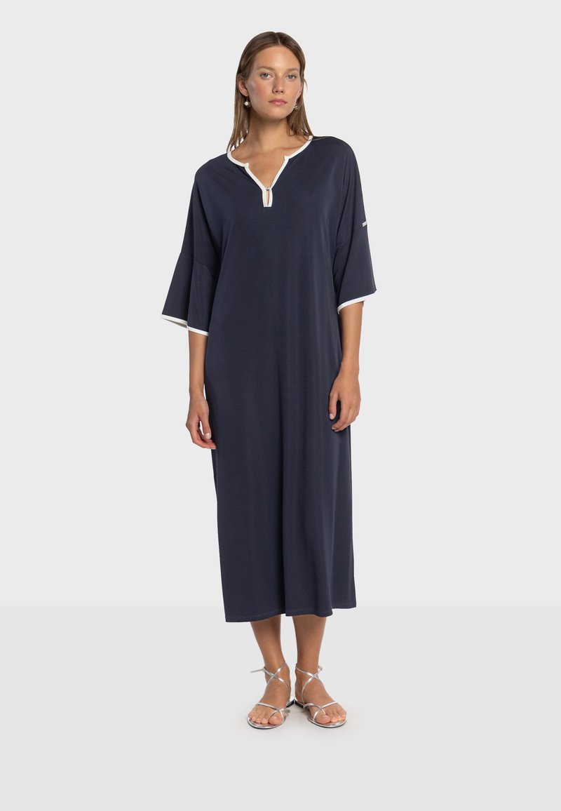 Abito blu navy con scollo a V e rifiniture bianche, vestibilità ampia, maniche tre quarti e lunghezza a metà polpaccio, realizzato in tessuto leggero.