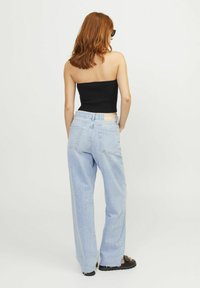 Zwart geribbeld strapless top gecombineerd met lichtblauwe high-waisted wijde jeans en zwarte sandalen, met een casual pasvorm en achterzakken.